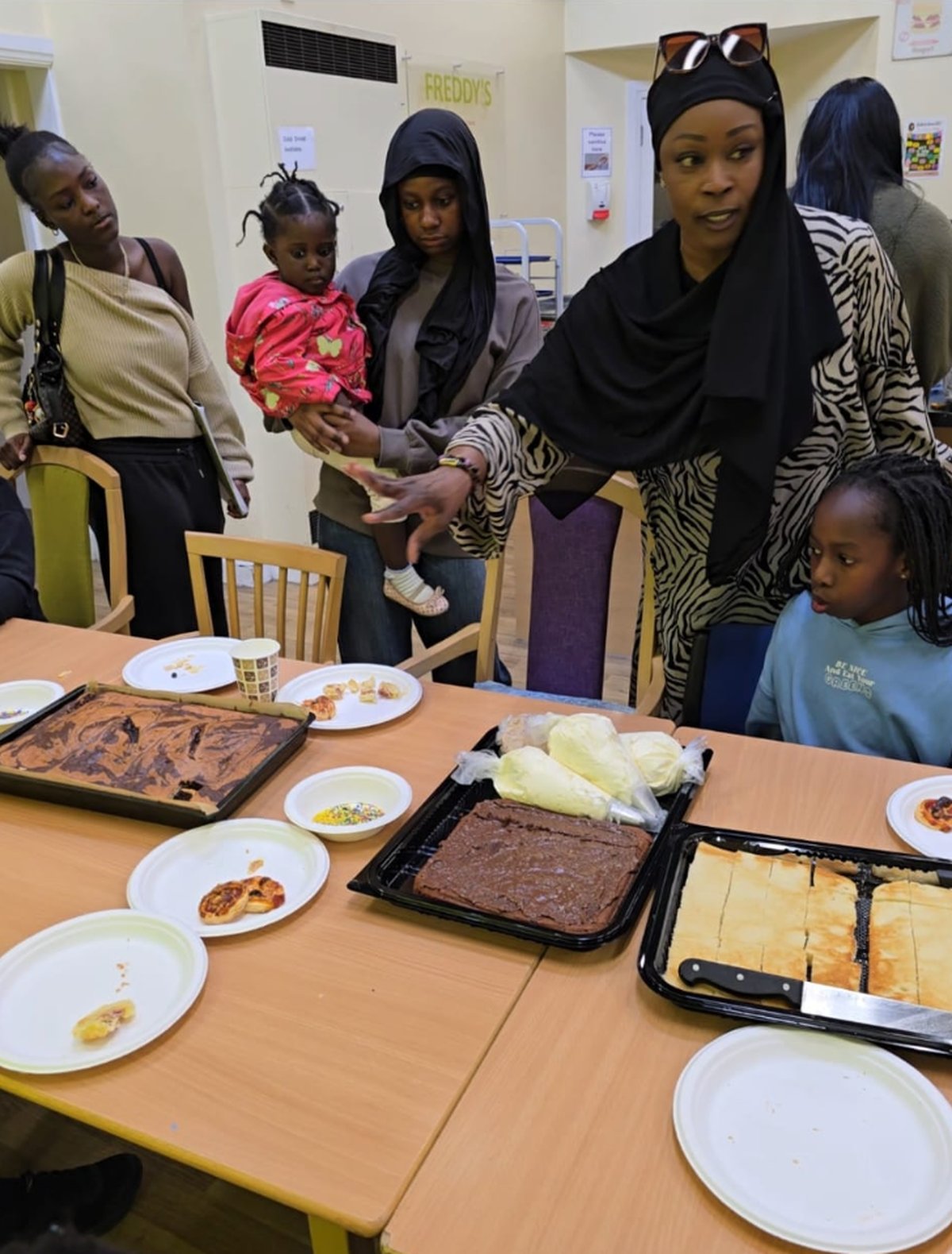 Families gathered around a table decorating cakes and pastries at a Senegalese baking session