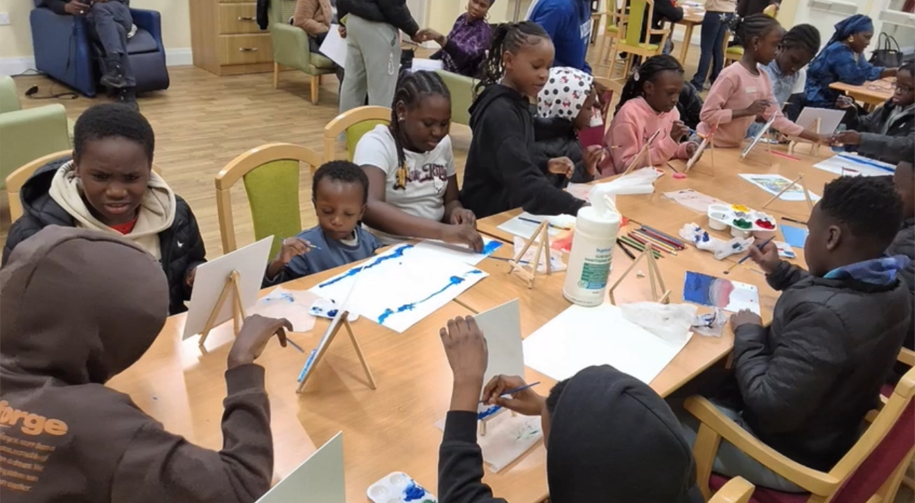Children around a table painting on canvases